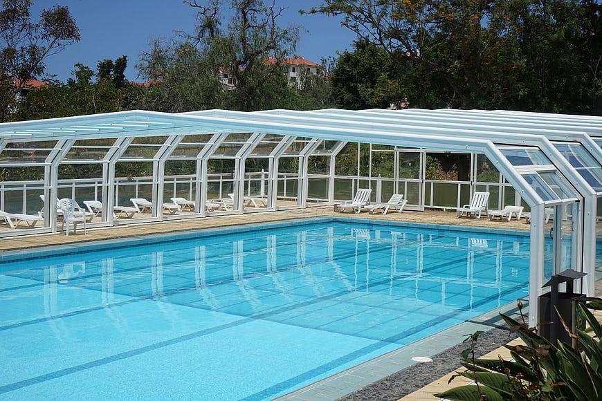 Modern outdoor swimming pool with white pergola and lounge chairs