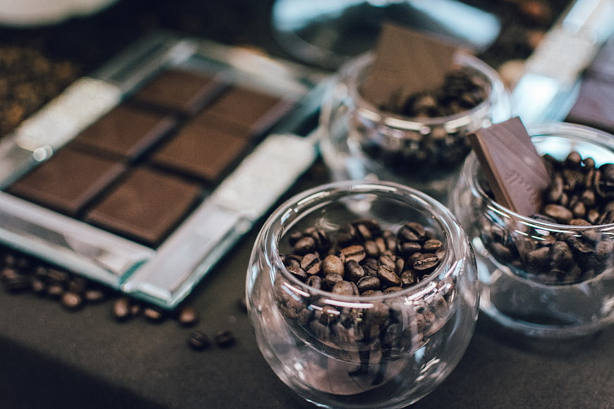 Dark chocolate bar and coffee beans in glass jars