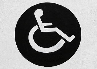 Black and white wheelchair accessibility symbol painted on textured wall