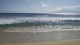 Sunny Beach Ocean Waves with Distant Mountain View