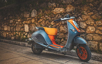 Vintage Blue and Orange Scooter Parked Against Stone Wall