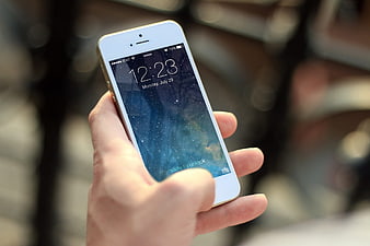 Hand holding white smartphone with galaxy wallpaper