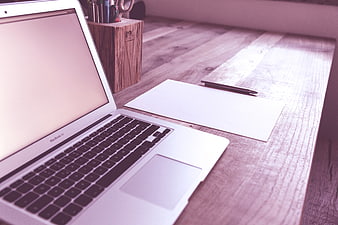 Modern Workspace with Laptop, Paper, and Pen on Wooden Desk