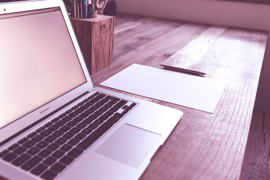 Modern Workspace with Laptop, Paper, and Pen on Wooden Desk
