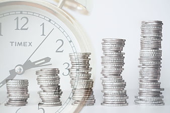 Ascending coin stacks in front of a Timex clock face