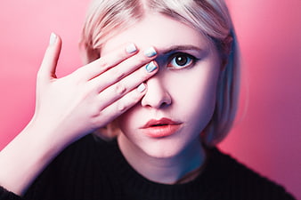 Blonde Woman Covering One Eye With Hand Against Pink Background