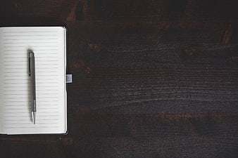 Minimalist notebook and pen on dark wooden desk background