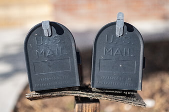 Two black USPS mailboxes on a wooden post