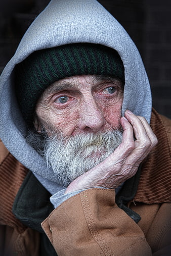 Close-up portrait of elderly homeless man with gray beard