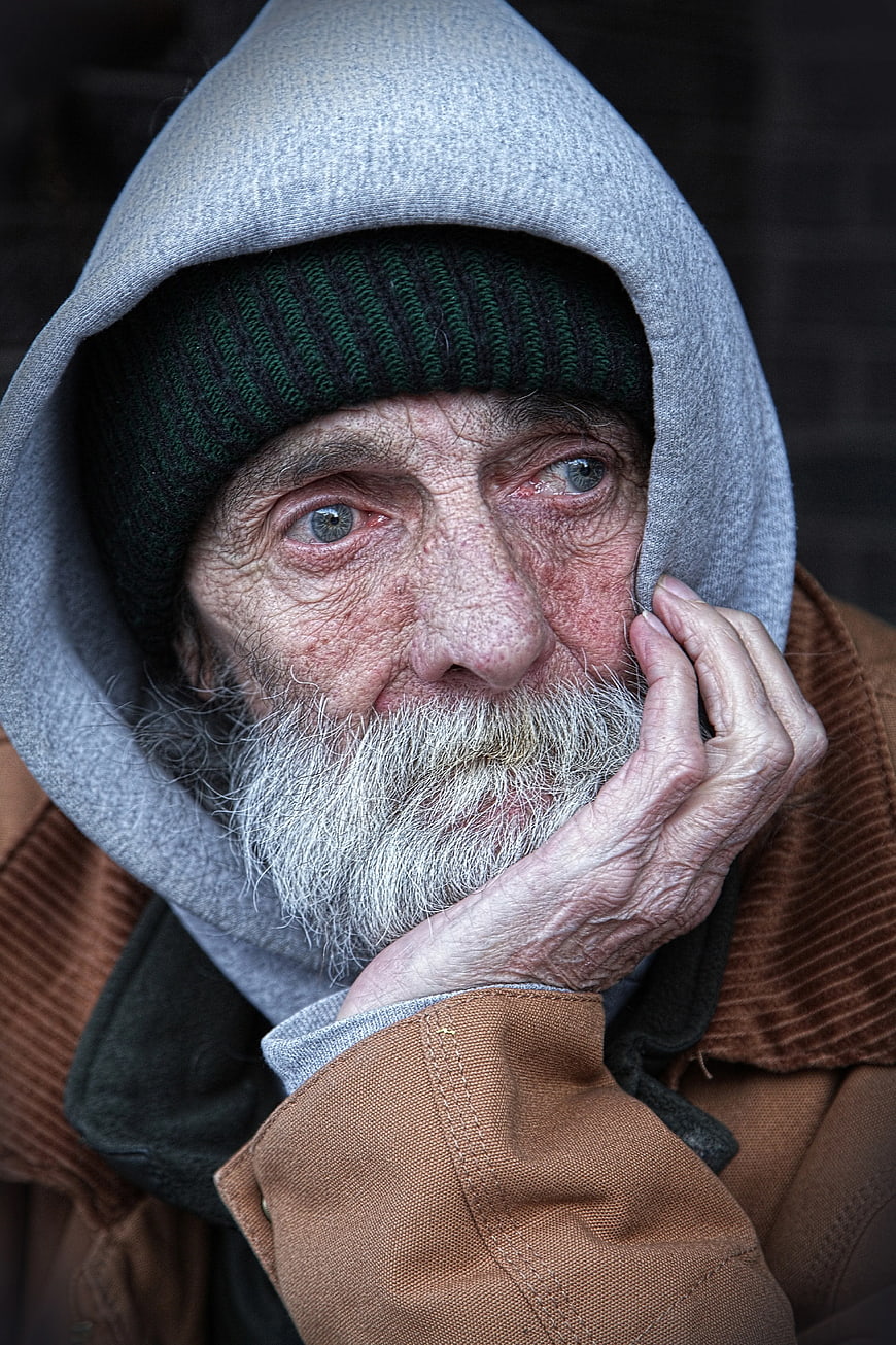 Close-up portrait of elderly homeless man with gray beard