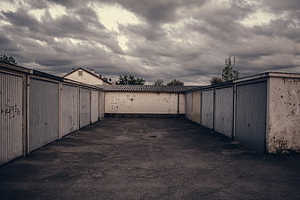 Empty Gritty Parking Lot With Garage Doors Under Dramatic Cloudy Sky