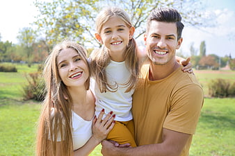 Happy family portrait with father, mother, and daughter in park