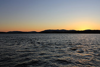 Sunset over Lake with Silhouetted Mountains and Rippling Water