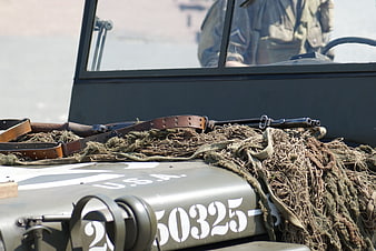 Close-up of WWII military jeep with camouflage netting and rifle
