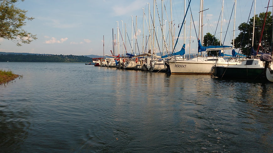 Sailboats docked in a calm lake harbor with blue sails