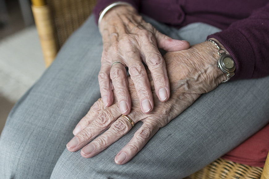 Close-up of elderly woman's wrinkled hands resting on lap