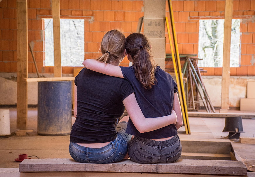 Two women hugging on construction site renovation