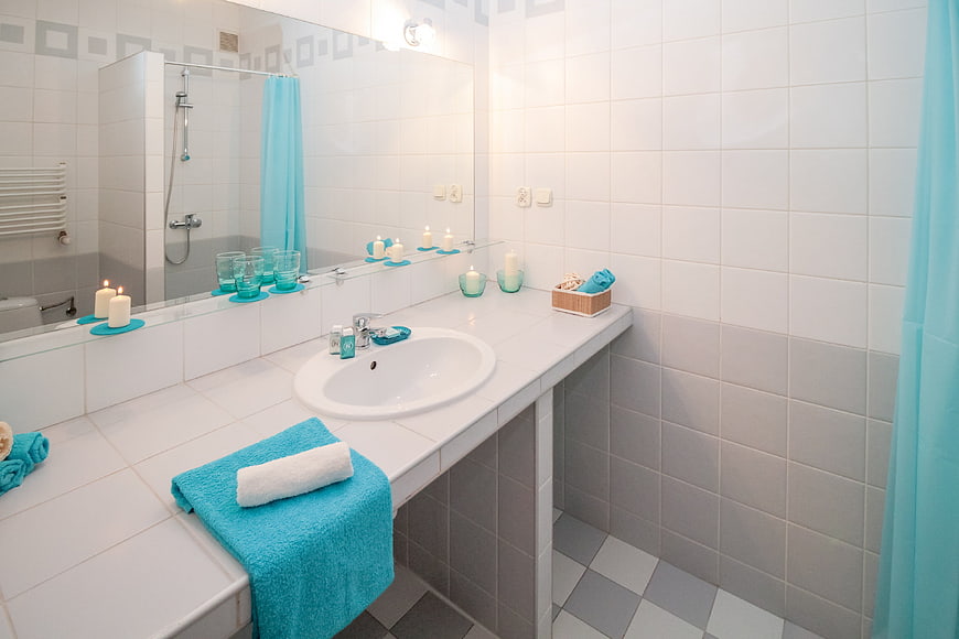 Clean white bathroom with turquoise towels and candles