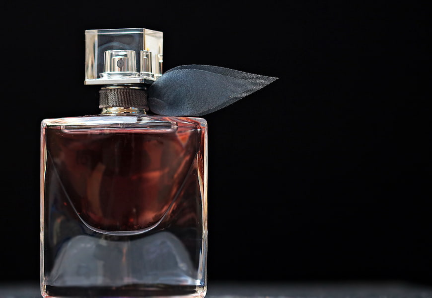 Luxury perfume bottle with black ribbon on dark background