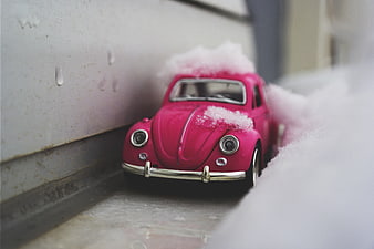 Pink toy car covered in snow on a windowsill