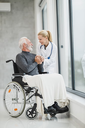 Smiling female doctor comforting elderly man in wheelchair