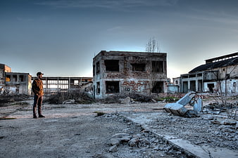 Man Standing in Abandoned Industrial Ruins at Dusk