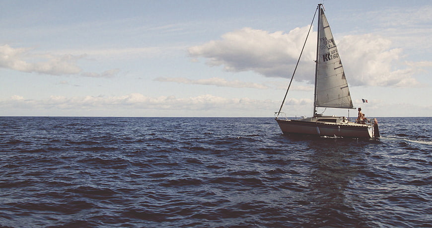 Sailboat Cruising on Open Ocean with Blue Sky
