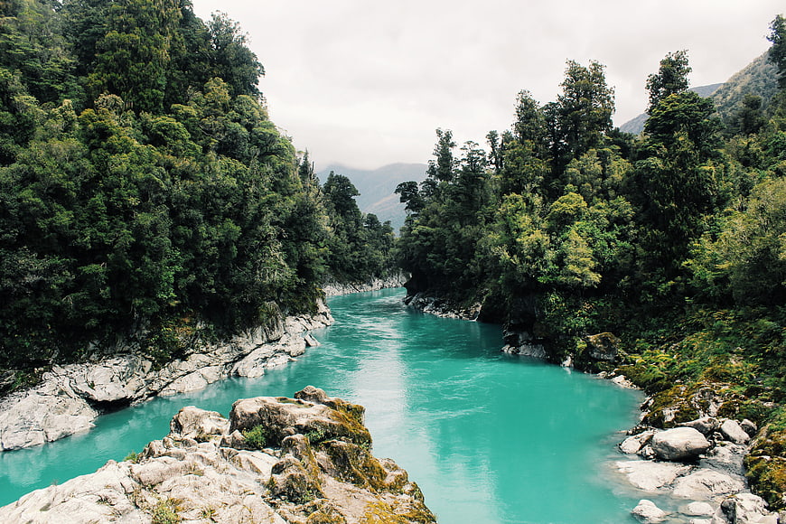 Turquoise river winding through lush green forest valley