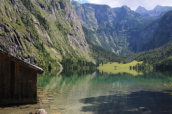 Serene Alpine Lake with Wooden Cabin and Mountain Reflections