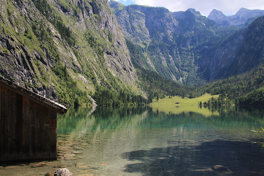 Serene Alpine Lake with Wooden Cabin and Mountain Reflections