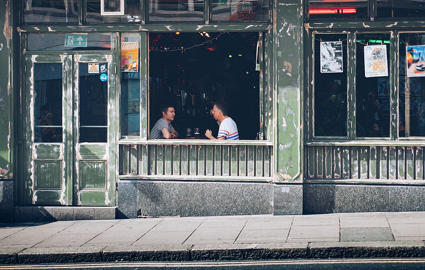 Two Men Talking in a Vintage Green Restaurant Window
