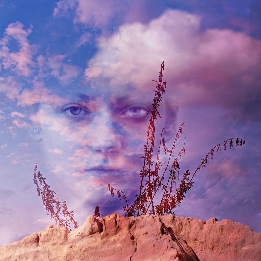 Surreal double exposure portrait of a woman's face blended with clouds and desert plants