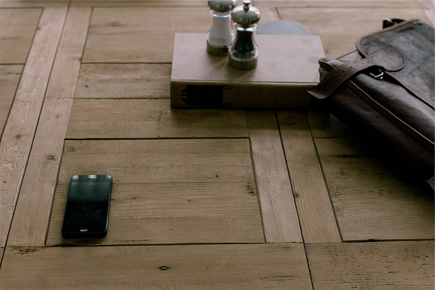Smartphone, leather bag, and book on rustic wooden table