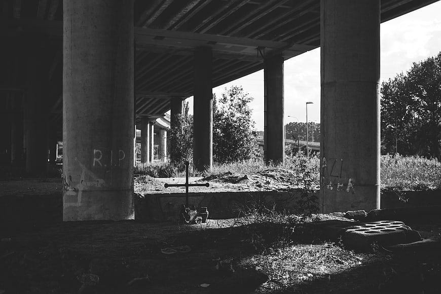 Black and white photo of makeshift grave under concrete bridge