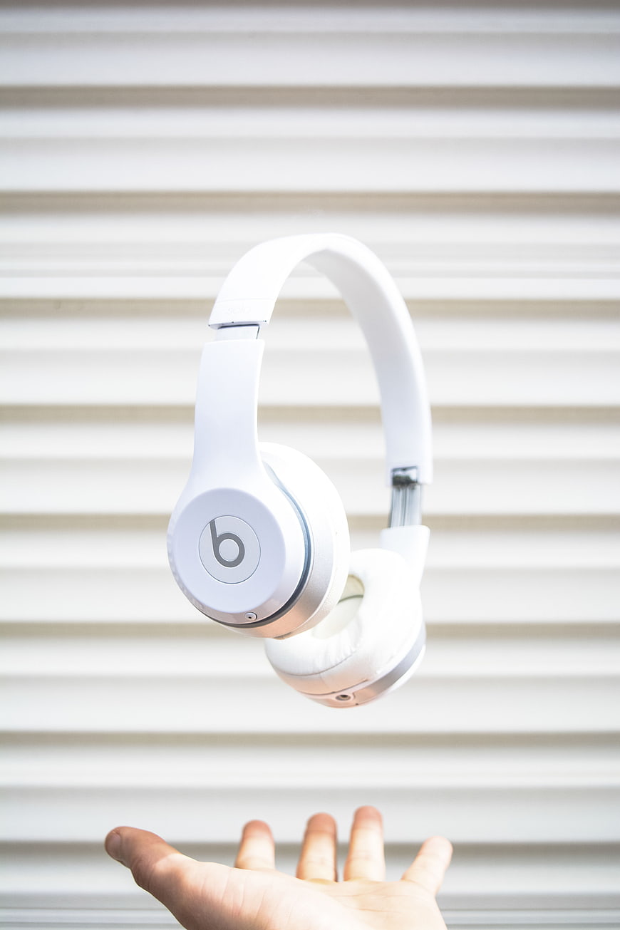 White headphones floating above hand against striped background