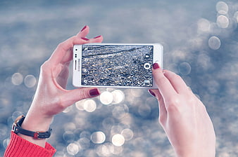 Woman taking photo with smartphone against bokeh background