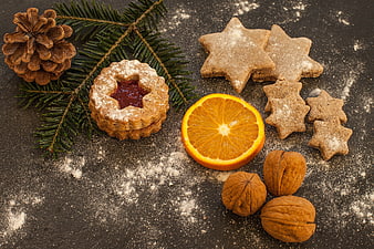 Christmas cookies, orange slice, and pine cone on dark slate