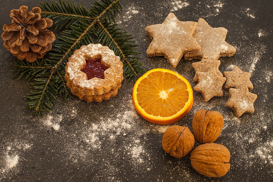 Christmas cookies, orange slice, and pine cone on dark slate