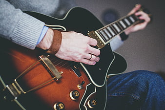 Close-up of hands playing a hollow-body electric guitar