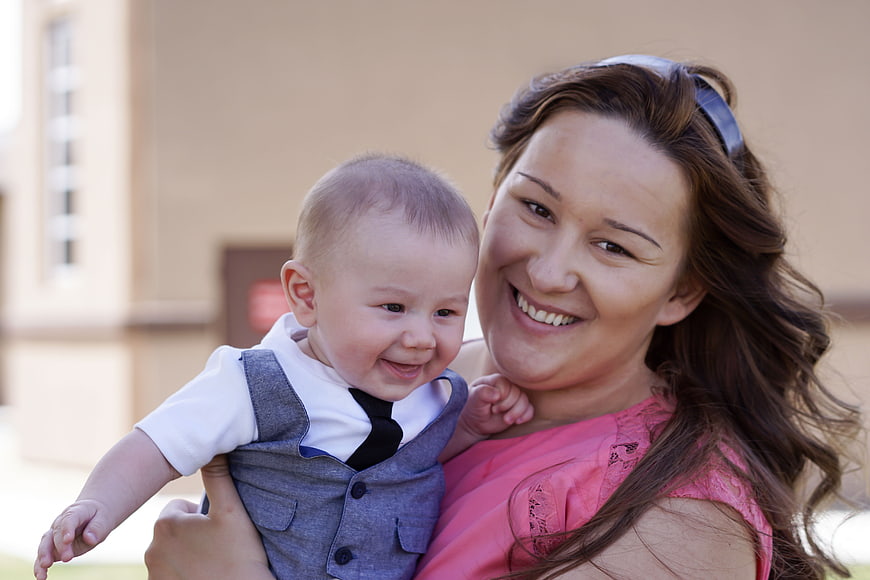 Smiling Mother Holding Happy Baby Boy Outdoors