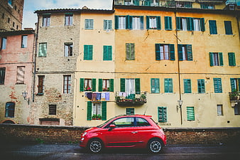 Red Fiat 500 parked in front of colorful Italian buildings