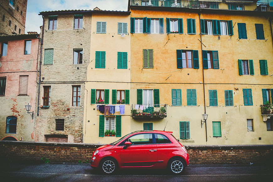 Red Fiat 500 parked in front of colorful Italian buildings