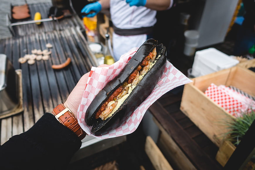 Hand holding black squid ink sub with shrimp
