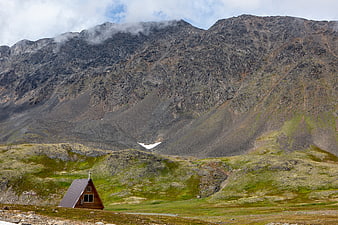 Small A-frame cabin in vast rocky mountain landscape