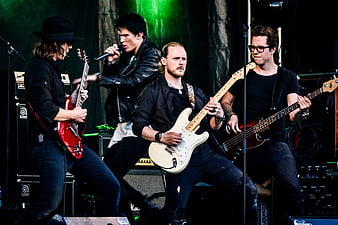 Rock band performing live on stage with electric guitars