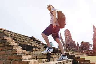 Traveler with camera climbing ancient temple ruins