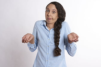 Surprised woman with braided hair shrugging in blue shirt