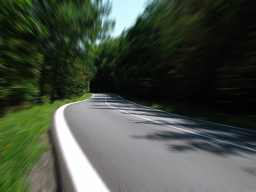 Motion blur view of winding country road through forest