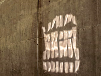 Abstract sunlight shadow pattern on textured concrete wall