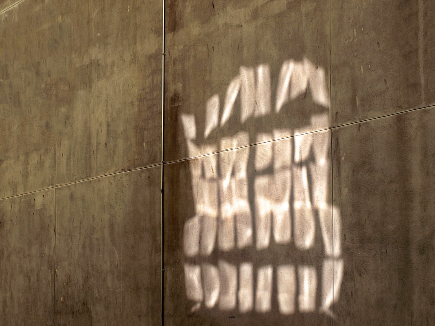 Abstract sunlight shadow pattern on textured concrete wall